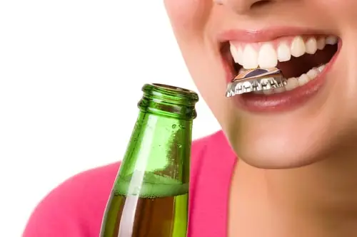 woman opening bottle with teeth