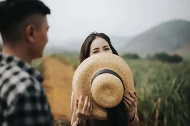woman hides her smile behind her hat